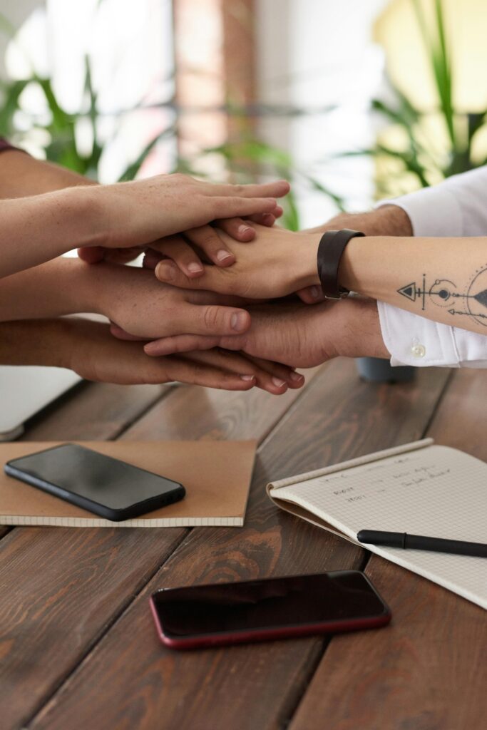 Hands from a diverse team stack on a table symbolizing unity and teamwork